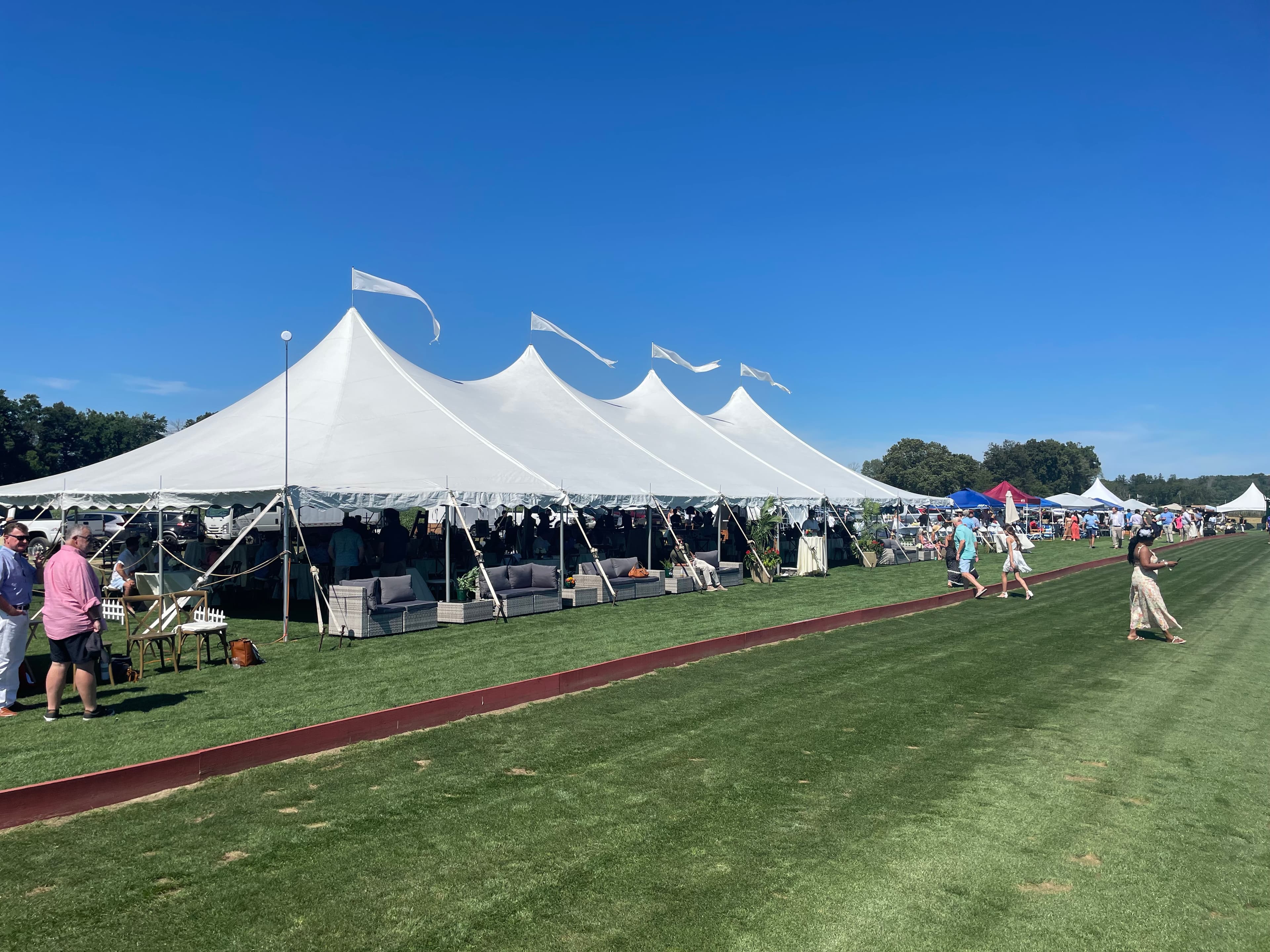 Outdoor wedding tent rental setup with seating and flooring